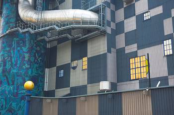 Sininen rakennus, jossa suuret metalliset putket kiertävät ulkoseinällä.