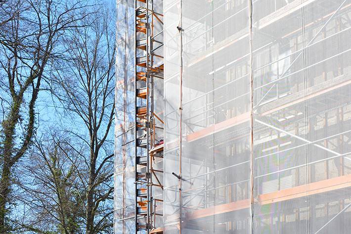Monikerroksinen rakennus, jota korjataan. Ulkoseinillä rakennustelineet ja suojakankaat.
